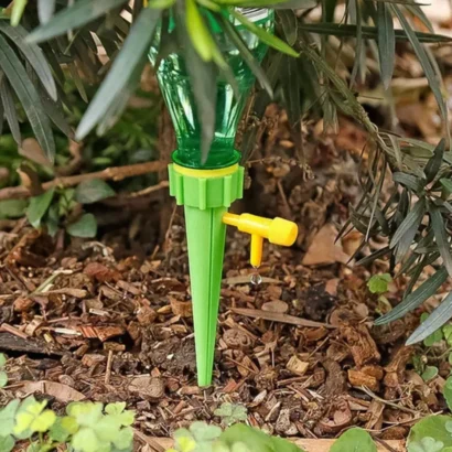Automatic watering spikes inserted in indoor plant pot showing slow water drip system for home gardening.